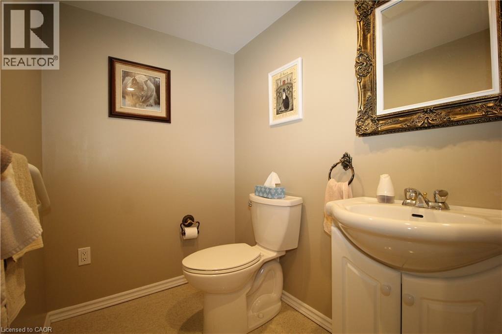 Pedestal sink with an integrated vanity cabinet, decorative wall mirror, and neutral wall paint - 14 Berkley Crescent, Simcoe, ON - Indoor Photo Showing Bathroom