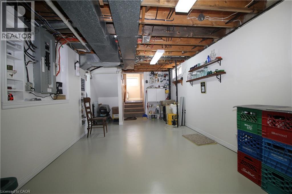 Unfinished basement featuring exposed wood beams, overhead fluorescent lighting, and a utility sink - 14 Berkley Crescent, Simcoe, ON - Indoor Photo Showing Basement