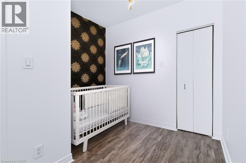 Wood-finish flooring, accent wall with decorative patterned wallpaper, and bi-fold closet doors - 442 King William Street, Hamilton, ON - Indoor