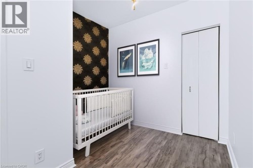 Wood-finish flooring, accent wall with decorative patterned wallpaper, and bi-fold closet doors - 442 King William Street, Hamilton, ON - Indoor