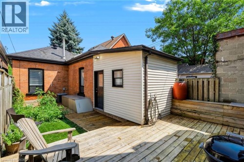 Expansive wood deck with attached siding-clad extension, complementing the brick exterior of the main structure - 442 King William Street, Hamilton, ON - Outdoor With Deck Patio Veranda With Exterior