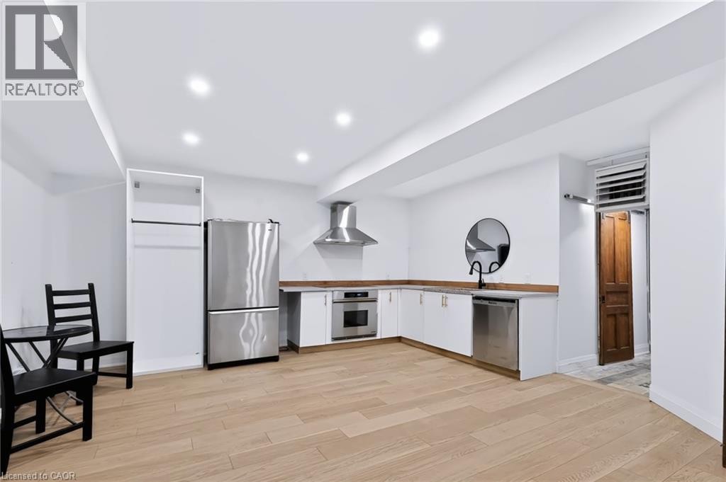 Recessed lighting illuminates the space, featuring wood-finish flooring, white cabinetry, and stainless steel appliances - 442 King William Street, Hamilton, ON - Indoor Photo Showing Kitchen