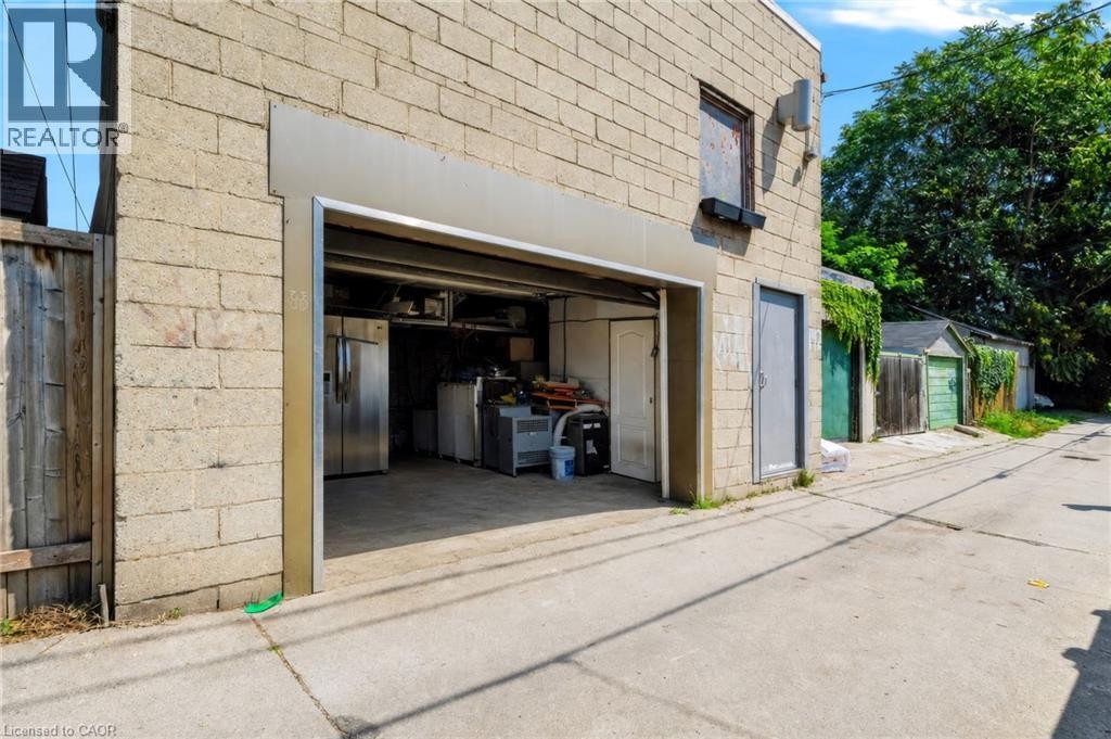 Light-toned concrete block exterior with an open garage entrance - 442 King William Street, Hamilton, ON - Outdoor With Exterior