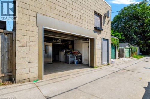 Light-toned concrete block exterior with an open garage entrance - 442 King William Street, Hamilton, ON - Outdoor With Exterior
