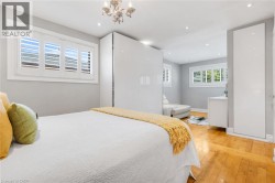 Hardwood flooring, recessed lighting, white built-in cabinetry, white window shutters, and a chandelier fixture - 