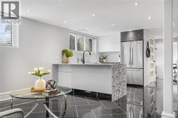 Kitchenette with contemporary flat-panel cabinetry, a stone countertop, and a stainless steel refrigerator - 