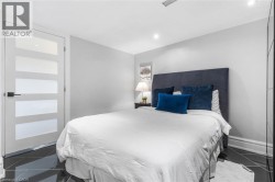 Black tile flooring with geometric grout lines, a five-panel frosted glass door, recessed ceiling lighting, a dark upholstered headboard, and a built-in mirrored wardrobe - 