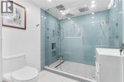 Glass-enclosed shower with blue-tiled walls, built-in shower niches, and a rainfall showerhead - 