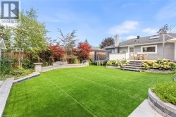 Expansive backyard with artificial turf, stone retaining walls, and a multi-level patio - 