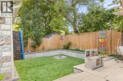 Manicured backyard featuring a built-in fire pit, artificial turf, and a wood-slat privacy fence - 