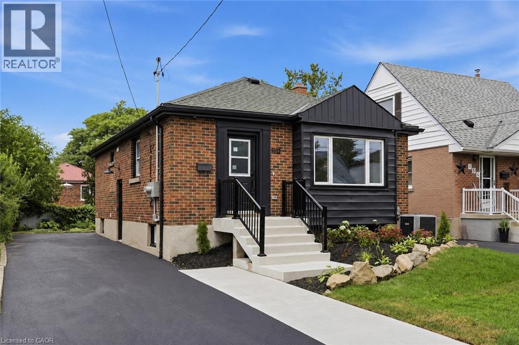 Brick exterior with contrasting black siding, dark shingle roof, paved driveway, and concrete walkway - 156 East 36Th Street, Hamilton, ON - Outdoor