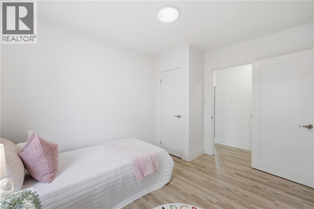 Recessed circular ceiling light, light wood-finish flooring, two white interior doors, and white painted walls - 156 East 36Th Street, Hamilton, ON - Indoor Photo Showing Bedroom