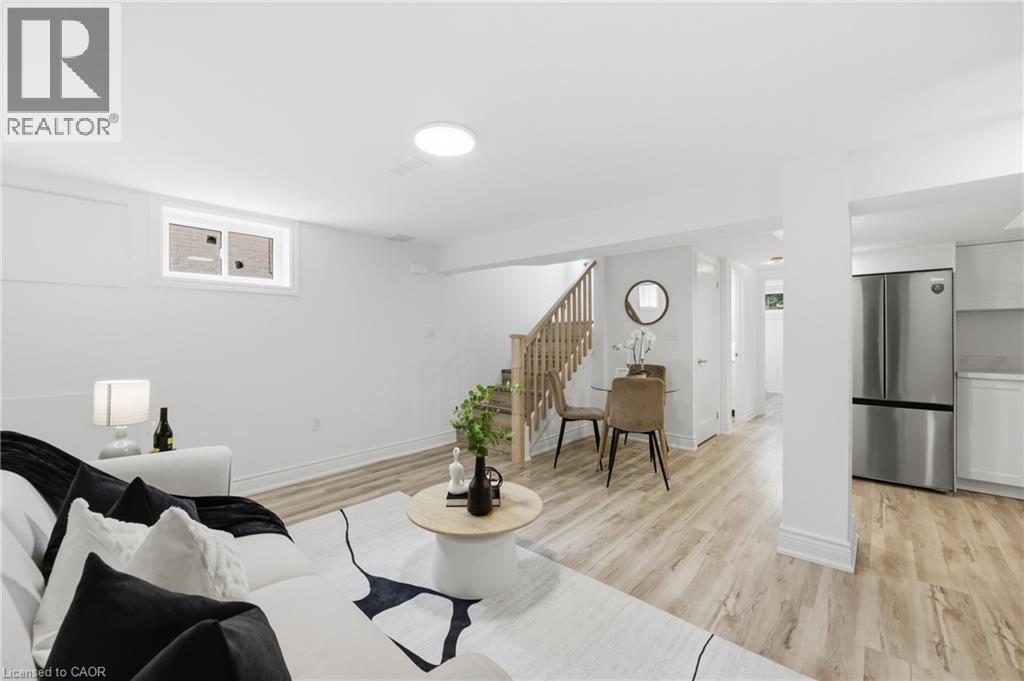 Expansive open-concept space featuring recessed lighting, wood-finish flooring, a contemporary staircase with wooden railings, and a built-in stainless steel refrigerator - 156 East 36Th Street, Hamilton, ON - Indoor Photo Showing Living Room