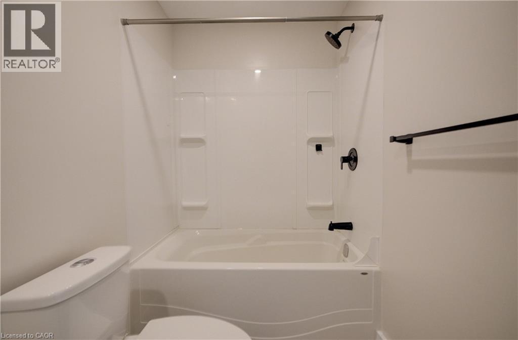 Tub and shower combination featuring a white surround, matte black fixtures, and integrated shelving - 361 Prospect Avenue, Kitchener, ON - Indoor Photo Showing Bathroom
