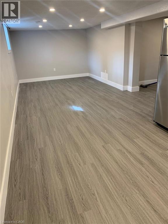 Spacious room featuring wood-finish flooring, recessed ceiling lighting, a window, and neutral wall paint - 361 Prospect Avenue, Kitchener, ON - Indoor