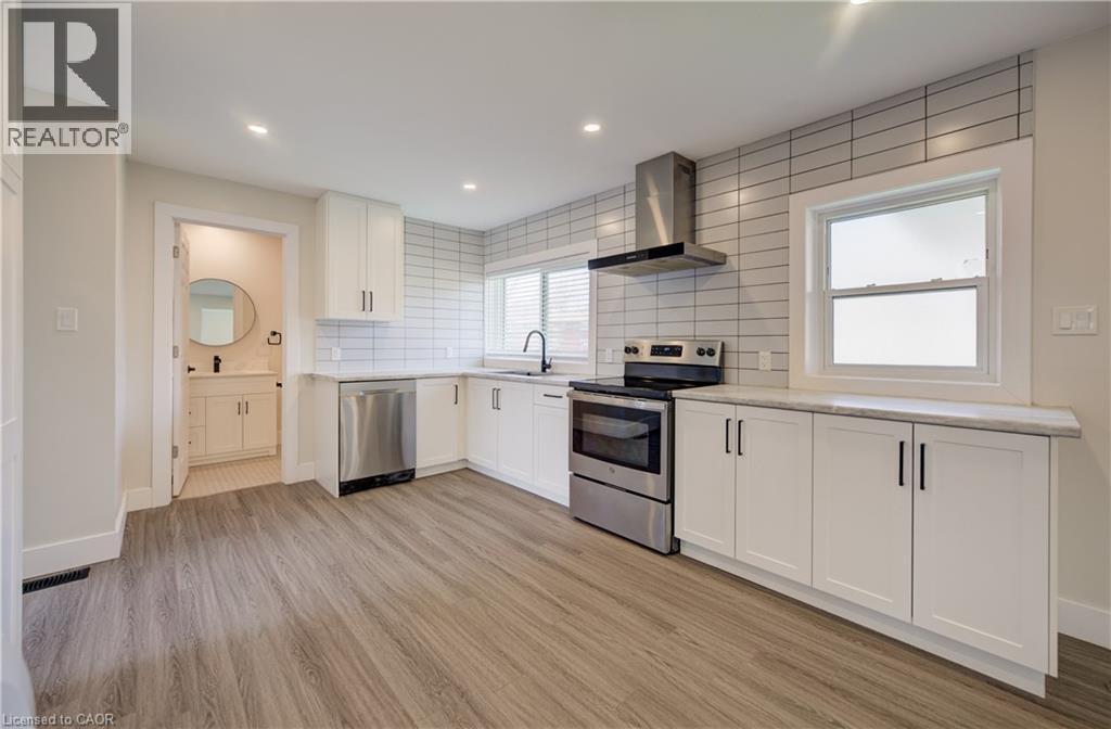 Contemporary kitchen featuring white shaker cabinetry, stainless steel appliances, light wood-finish flooring, and subway tile backsplash - 361 Prospect Avenue, Kitchener, ON - Indoor Photo Showing Kitchen