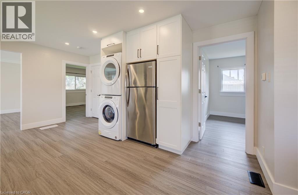 Laundry area with stacked appliances, white cabinetry, and stainless steel refrigerator - 361 Prospect Avenue, Kitchener, ON - Indoor Photo Showing Other Room