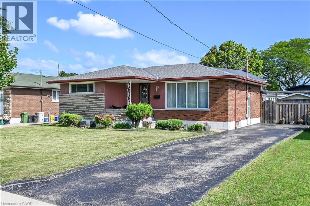 Brick and stone facade with a covered front porch, asphalt driveway, and a fenced side yard - 5 Kentley Drive, Hamilton, ON - Outdoor