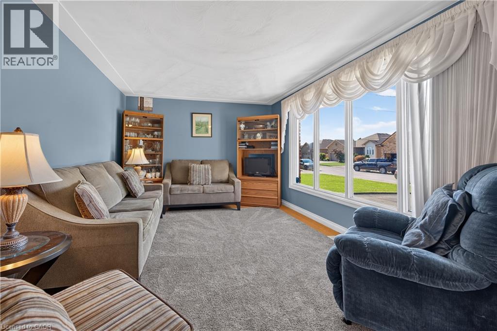 Spacious room featuring light blue walls, gray carpet, and a large multi-pane window with white trim - 5 Kentley Drive, Hamilton, ON - Indoor Photo Showing Living Room