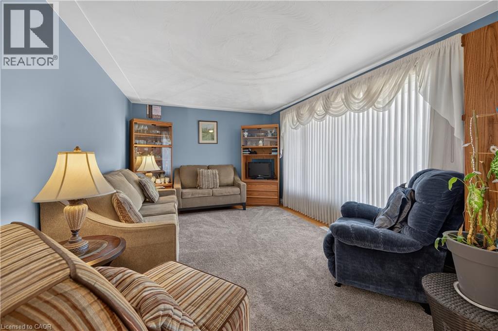 Wall-to-wall carpeting, light blue wall paint, and vertical window blinds - 5 Kentley Drive, Hamilton, ON - Indoor Photo Showing Living Room