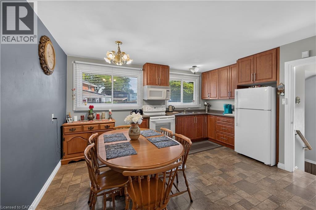 Kitchen featuring wood-finish cabinetry, white appliances, and a window with blinds - 5 Kentley Drive, Hamilton, ON - Indoor