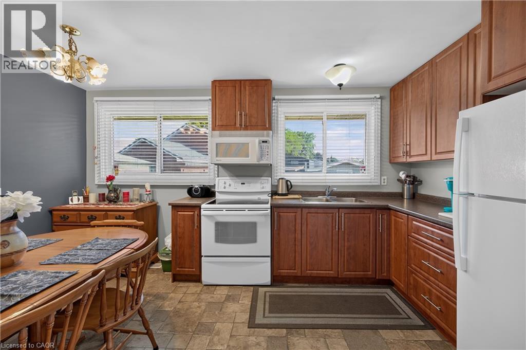 Kitchen featuring wood-finish cabinetry, white appliances, and a double window - 5 Kentley Drive, Hamilton, ON - Indoor Photo Showing Kitchen With Double Sink