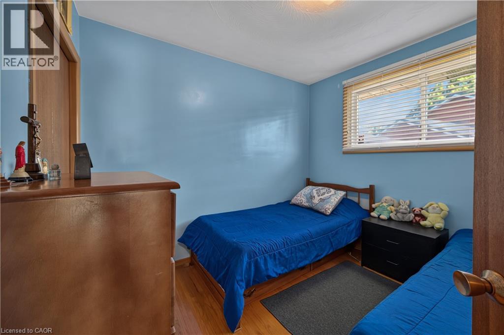 Wood-finish flooring with a window featuring horizontal blinds - 5 Kentley Drive, Hamilton, ON - Indoor Photo Showing Bedroom