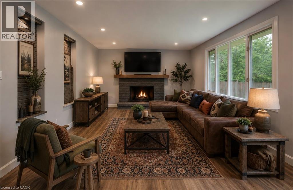Recessed fireplace with a wood mantel, wood-finish flooring, recessed lighting, expansive windows, and built-in wall niches with brick-finish backing - 244 Royal Street, Waterloo, ON - Indoor Photo Showing Living Room With Fireplace