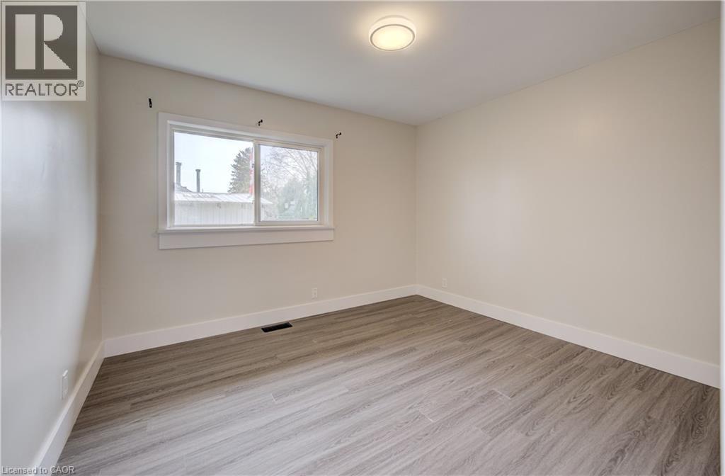 Neutral-toned room featuring wood-finish flooring, a white trim window, and a flush-mount ceiling light - 361 Prospect Avenue, Kitchener, ON - Indoor Photo Showing Other Room