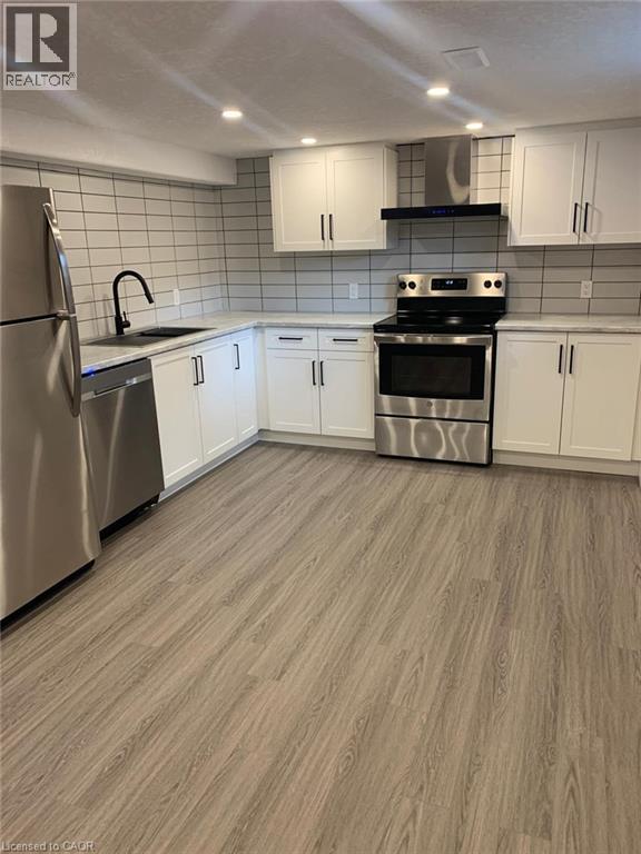 Modern kitchen featuring stainless steel appliances, white shaker cabinetry, and wood-finish flooring - 361 Prospect Avenue, Kitchener, ON - Indoor Photo Showing Kitchen