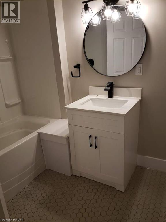 Bathroom featuring a white vanity with a rectangular sink, a black single-handle faucet, and a circular black-framed mirror - 361 Prospect Avenue, Kitchener, ON - Indoor Photo Showing Bathroom