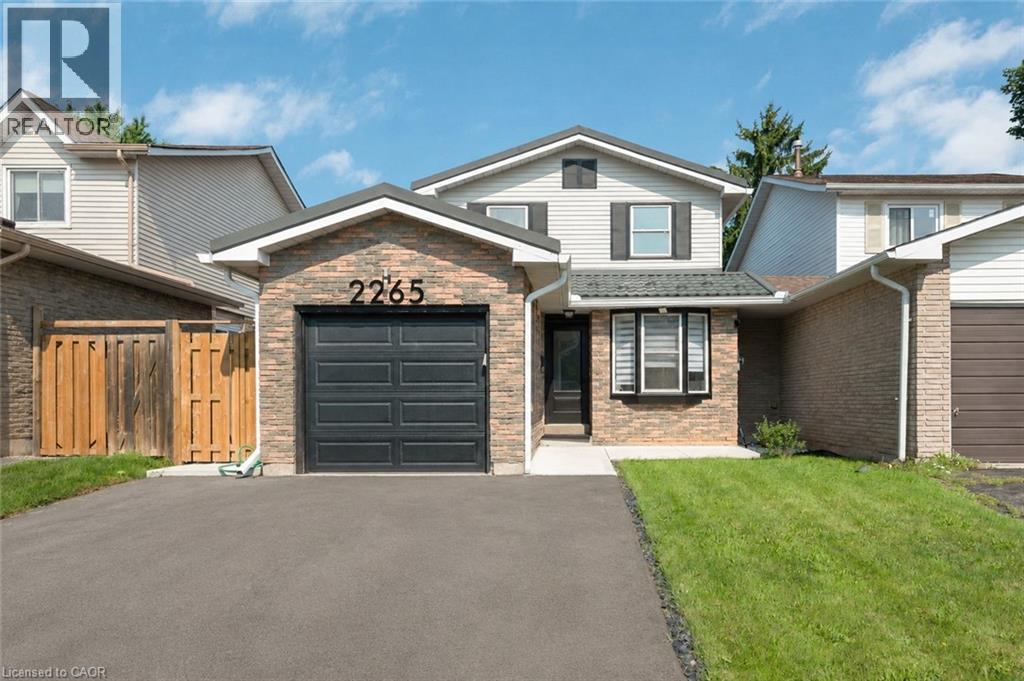 Brick facade with integrated garage, dark garage door, and a paved driveway - 2265 Middlesmoor Crescent, Burlington, ON - Outdoor