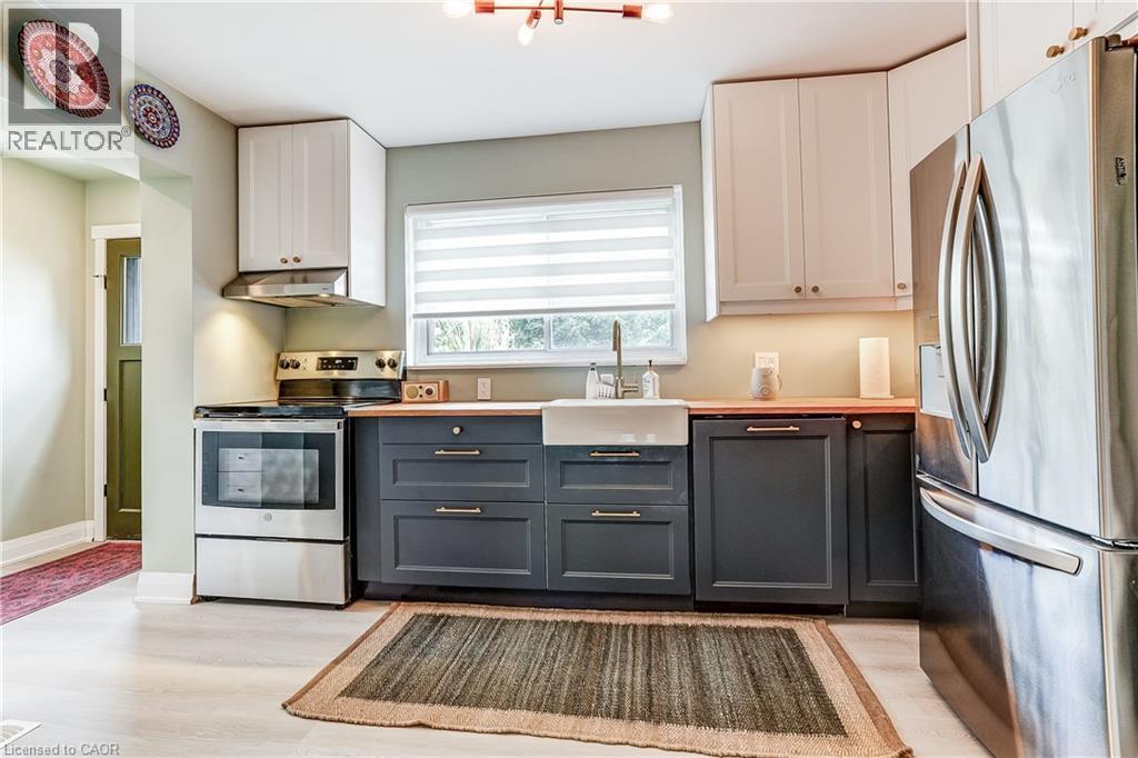 Modern kitchen featuring two-tone cabinetry, stainless steel appliances, wood-finish countertops, and an apron-front sink - 2488 Brookhurst Road, Mississauga, ON - Indoor Photo Showing Kitchen