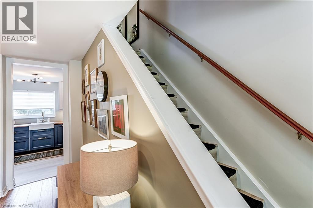 Hardwood flooring, wood stair railing, recessed lighting, white farmhouse sink, and dark blue cabinetry - 2488 Brookhurst Road, Mississauga, ON - Indoor Photo Showing Other Room