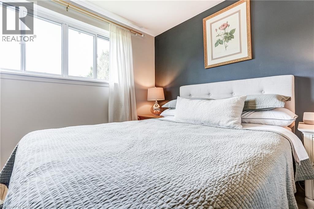 Large window with white trim, a tufted upholstered headboard, and a contrasting accent wall - 2488 Brookhurst Road, Mississauga, ON - Indoor Photo Showing Bedroom