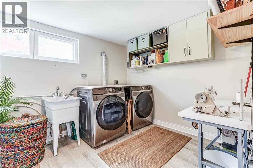 Laundry area featuring a utility sink, light wood-finish flooring, and upper cabinetry for storage - 2488 Brookhurst Road, Mississauga, ON - Indoor Photo Showing Laundry Room