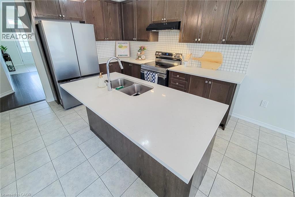 Kitchen featuring a large center island with an undermount double sink, stainless steel appliances, dark wood-finish cabinetry, and a white subway tile backsplash - 11 Esther Crescent, Thorold, ON - Indoor Photo Showing Kitchen With Stainless Steel Kitchen With Double Sink