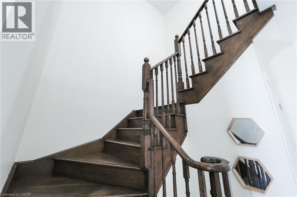 Wood-finish staircase with turned balusters and a curved handrail, set against crisp white walls - 11 Esther Crescent, Thorold, ON - Indoor Photo Showing Other Room