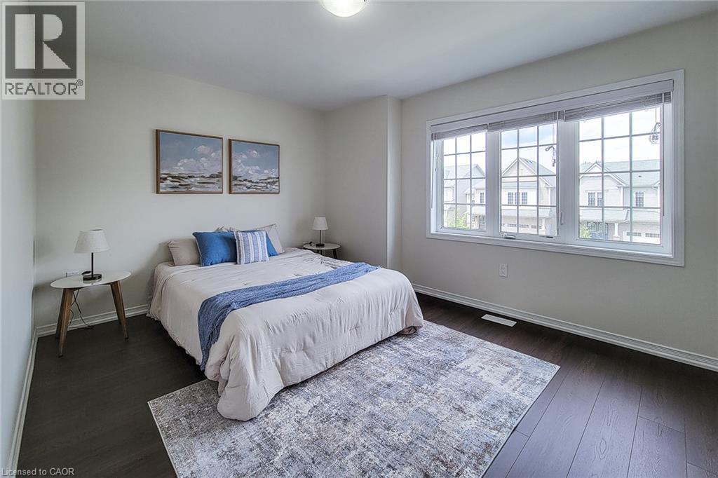 Dark wood-finish flooring, white walls, and a large multi-pane window create a bright and inviting atmosphere - 11 Esther Crescent, Thorold, ON - Indoor Photo Showing Bedroom