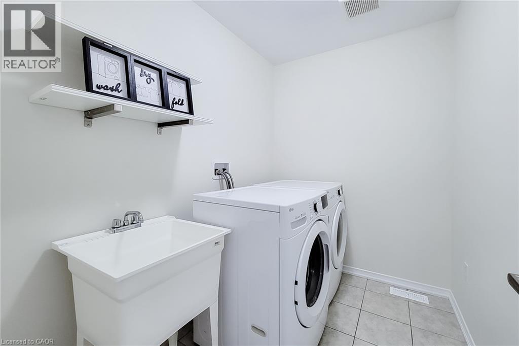 Utility room featuring tiled flooring, a built-in utility sink with a chrome faucet, and integrated shelving - 11 Esther Crescent, Thorold, ON - Indoor Photo Showing Laundry Room