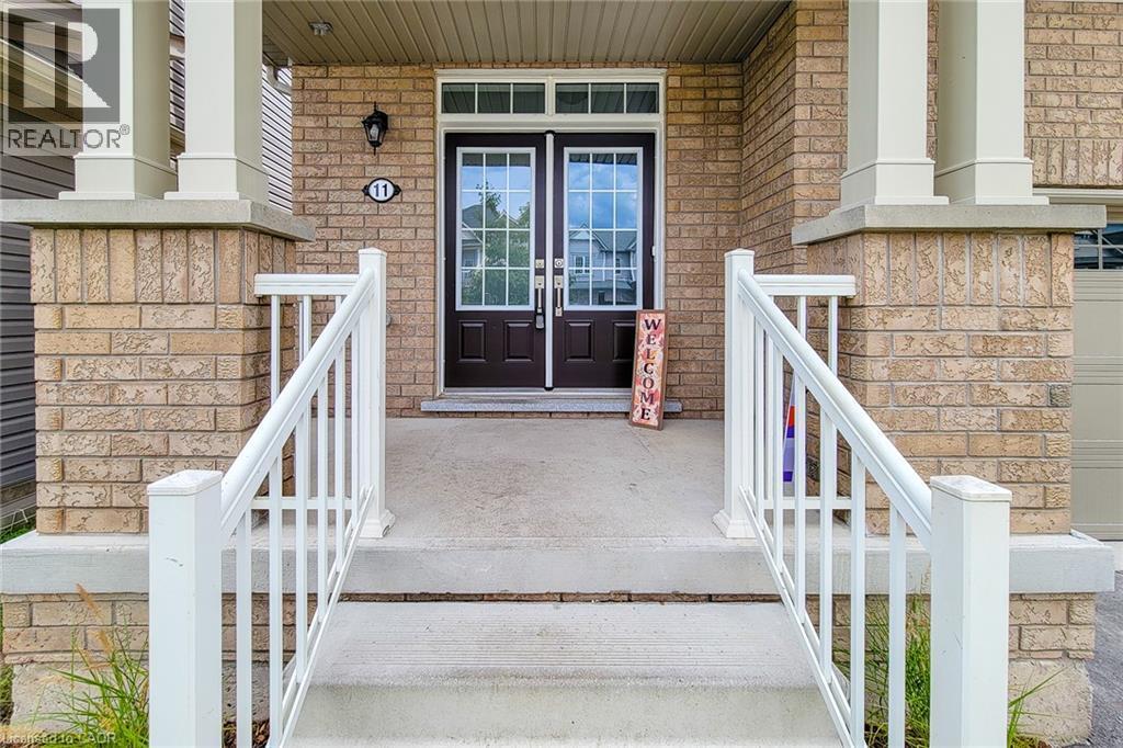 Brick facade with white column accents, concrete steps with white railings, and double entry doors with integrated glass panels - 11 Esther Crescent, Thorold, ON - Outdoor With Exterior