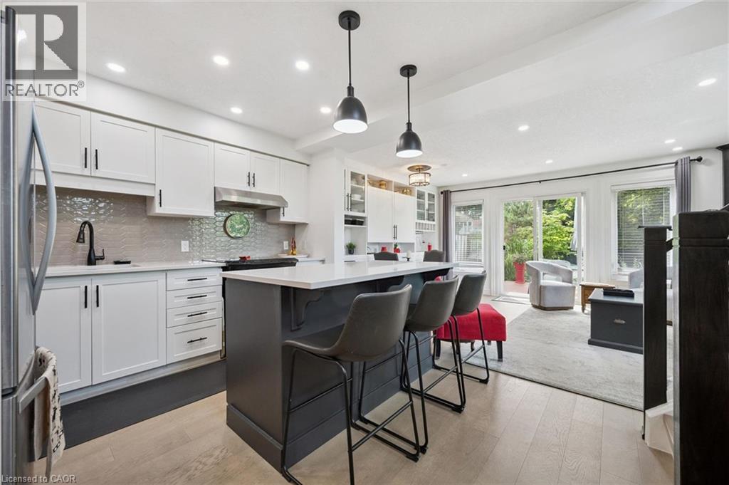 Kitchen featuring white cabinetry, a gray tiled backsplash, stainless steel appliances, and a central island with counter seating - 439 Beaver Creek Road, Waterloo, ON - Indoor Photo Showing Kitchen With Upgraded Kitchen