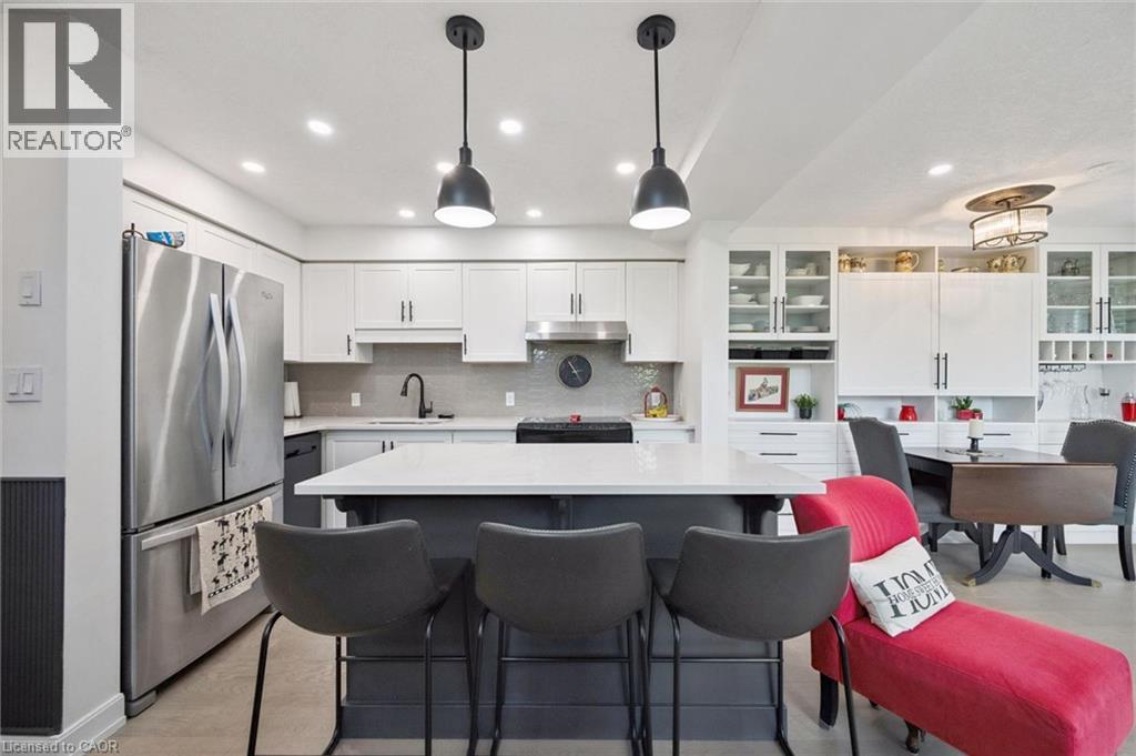 Contemporary kitchen featuring a center island with seating, pendant lighting, stainless steel appliances, white cabinetry, and a tile backsplash - 439 Beaver Creek Road, Waterloo, ON - Indoor Photo Showing Kitchen With Upgraded Kitchen