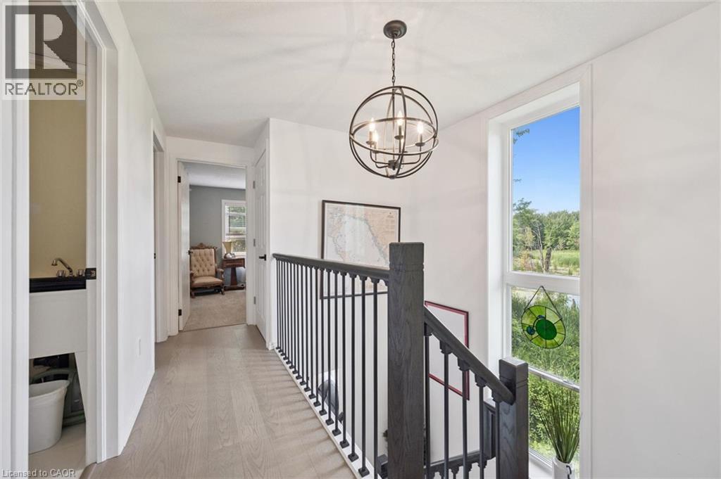 Hardwood-finish flooring, white walls, and a black metal chandelier - 439 Beaver Creek Road, Waterloo, ON - Indoor Photo Showing Other Room
