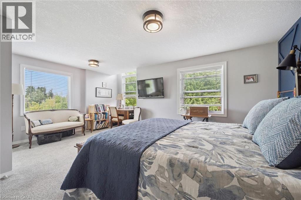 Recessed lighting fixtures, multiple windows with blinds, built-in shelving, carpeted flooring, and accent wall paneling - 439 Beaver Creek Road, Waterloo, ON - Indoor Photo Showing Bedroom