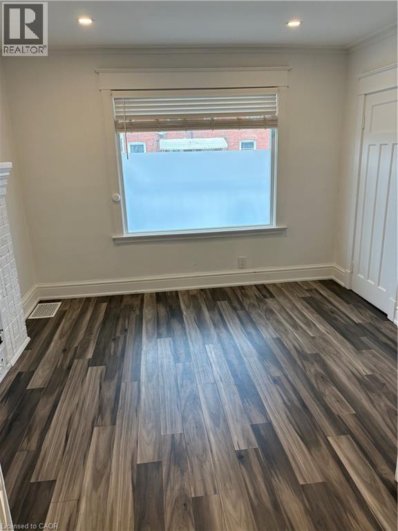 Unfurnished room featuring dark wood finished floors, ornamental molding, recessed lighting, and a brick fireplace - 1090 Cannon Street E Unit# 2, Hamilton, ON - Indoor Photo Showing Other Room