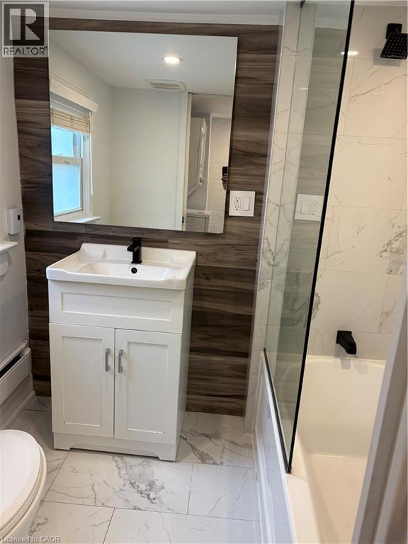 Full bath featuring marble finish flooring, vanity, shower / tub combination, recessed lighting, and a baseboard heating unit - 1090 Cannon Street E Unit# 2, Hamilton, ON - Indoor Photo Showing Bathroom