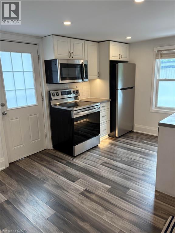 Kitchen with stainless steel appliances, white cabinetry, dark wood finished floors, tasteful backsplash, and recessed lighting - 1090 Cannon Street E Unit# 2, Hamilton, ON - Indoor Photo Showing Kitchen
