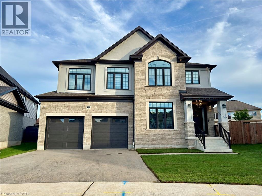Stone and stucco exterior with dark trim accents, a prominent arched window, two-car garage, and covered front entry - 923 Eaglecrest Court, Kitchener, ON - Outdoor With Facade