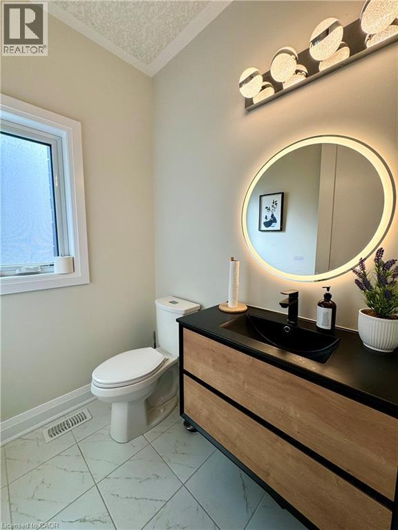 Modern vanity with a black countertop and basin, illuminated mirror, and tiled flooring - 923 Eaglecrest Court, Kitchener, ON - Indoor Photo Showing Bathroom